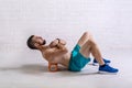 A young man in shorts is doing exercises on a foam roller on his back Royalty Free Stock Photo