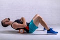 A young man in shorts is doing exercises on a foam roller on his back Royalty Free Stock Photo