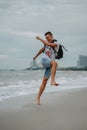 A young man in shorts and a t-shirt is having fun and actively playing with the sea. Running, jumping and having fun at Royalty Free Stock Photo