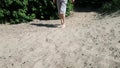 A young man in shorts is walking on the sand and limping. The disease is cerebral palsy. Lameness in adult