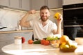 Man showing biceps muscles and peppers at table Royalty Free Stock Photo