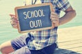 Young man showing a chalkboard with the text schools out, with a Royalty Free Stock Photo