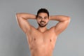 Young man showing hairless armpits after epilation on grey background Royalty Free Stock Photo