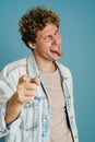 Young man showing his tongue and pointing finger at camera Royalty Free Stock Photo