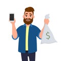 Young man is showing or holding money bag, cash bag. Man shows a blank or empty screen display of cell, mobile, smartphone in hand Royalty Free Stock Photo