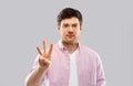 Young man showing three fingers over grey Royalty Free Stock Photo