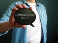 Young guy shows handwritten inscription Communication Skills.