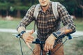 Young Man Shows A Hang Loose Shaka Surfer Sign By Hand Sitting On A Bicycle On Green Summer Meadow