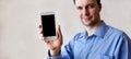 Young man shows smart phone in the right hand Royalty Free Stock Photo