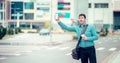 Young man on side of road hailing a taxi cab with a smart phone. Calling a taxi with a phone app concept