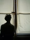 Young man silhouette in front of a big close window with copy space for your text