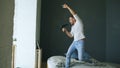 Young man singing to hair dryer and dancing rocknroll on bed in bedroom