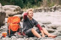 Young man sit barefoot on the mountain river bank Royalty Free Stock Photo