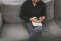 Young man sit down on the sofa while using mobile phone and drink coffee  relaxing at home Royalty Free Stock Photo