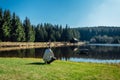 Young man sit on nice clean pond with wooden building and spring tree with blue sky