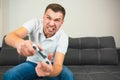 Young man sit in room during quarantine. Intense game and emotional guy using joystick or gamepad. Screaming out loud Royalty Free Stock Photo