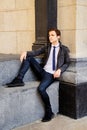 young man sits against backdrop of stone wall, looks to side with serious expression on his face Royalty Free Stock Photo