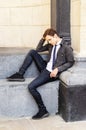 young man sits against backdrop of stone wall, looks to side with serious expression on his face Royalty Free Stock Photo