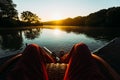 Young Man Sits In Armchair By The Lake And Meets Sunrise Or Sunset, Point Of View. Recreation Relaxation Concept