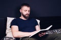 A young man sits on the bed and reads the Bible book. Prayer