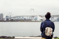 A young man sits on a bench in a cityscape on Odaiba Island in Tokyo. Back view Royalty Free Stock Photo