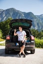 Young travel man sits in the car trunk take selfie photo on phone on mountaind background Royalty Free Stock Photo