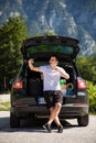 Young travel man sits in the car trunk take selfie photo on phone on mountaind background Royalty Free Stock Photo