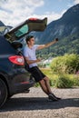 Young man sits in the car trunk take selfie photo on phone near beauty mountains background. Summer vocation Royalty Free Stock Photo