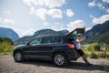 Young man sits in the car trunk take selfie photo on phone near beauty mountains background. Summer vocation Royalty Free Stock Photo