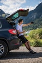 Young man sits in the car trunk take selfie photo on phone near beauty mountains background. Summer vocation Royalty Free Stock Photo