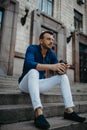 Young man sits and ponders on stairs with cup of coffee near building Royalty Free Stock Photo