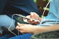 A young man sits on the street and uses a smartphone with headphones.