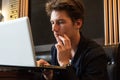 Young man sits at a table in front of a laptop Royalty Free Stock Photo