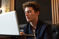 Young man sits at a table in front of a laptop Royalty Free Stock Photo