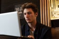 Young man sits at a table in front of a laptop. man working Royalty Free Stock Photo