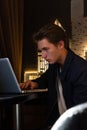 Young man sits at a table in front of a laptop