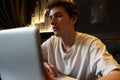 Young man sits at a table in front of a laptop. Royalty Free Stock Photo
