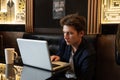 Young man sits at a table in front of a laptop Royalty Free Stock Photo