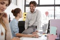 Young man sits on woman`s desk talking in open plan office Royalty Free Stock Photo