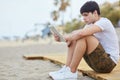 Young man sitting on beach holding tablet Royalty Free Stock Photo