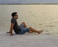 Young man sitting on the beach looking at the sea and relaxing. Lifesyle concept