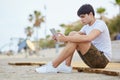 Young man sitting on beach using tablet Royalty Free Stock Photo