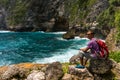 Young man sitting in beautiful cove on the rock and observing sea