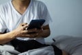 Young man sitting on the bed using smartphone at late night, Phone disease and Nomophobia. Healthy Concept