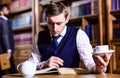 Young man sitting behind desk with teapot and book Royalty Free Stock Photo