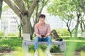 Young man sitting on bench in park, reading book, smiling and lo Royalty Free Stock Photo