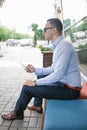 Young man is sitting on a bench with a smartphone in his hands.