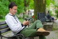 Young man sitting on the bench and using tablet device on beautiful spring day Royalty Free Stock Photo