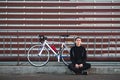 Young man sitting with a bicycle on a striped background, looking into the camera and smiling Royalty Free Stock Photo