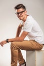 Young man sitting on a box while wearing glasses Royalty Free Stock Photo